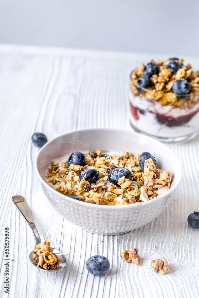 Homemade fitness granola with yoghurt and berries on white kitchen background