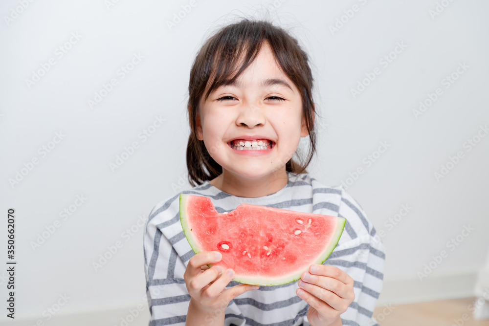 Asian little girl eating watermelon at home