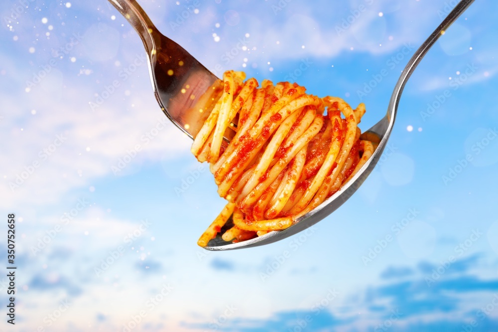 Classic metal fork with spaghetti on sky background