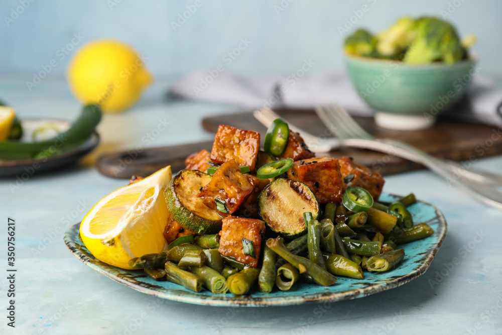 Plate with tasty tofu cheese and vegetables on color background