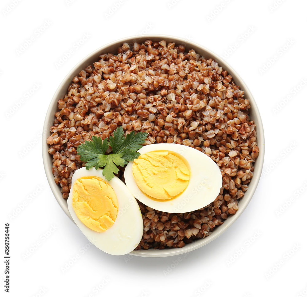 Bowl of tasty buckwheat porridge and eggs on white background