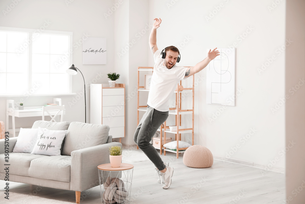 Handsome man dancing and listening to music at home