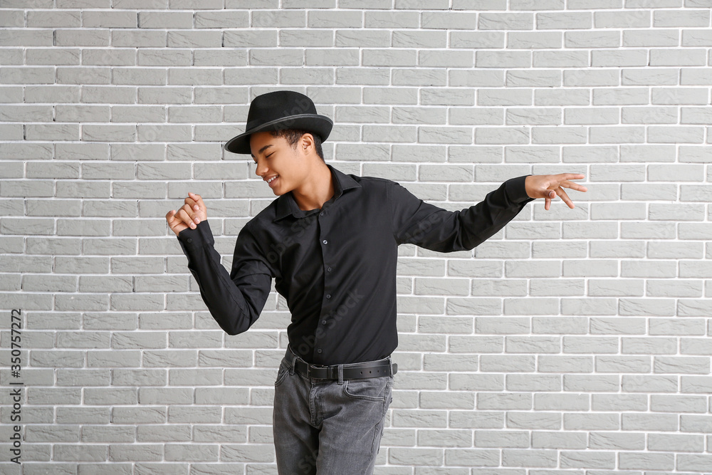 African-American teenager dancing against brick background