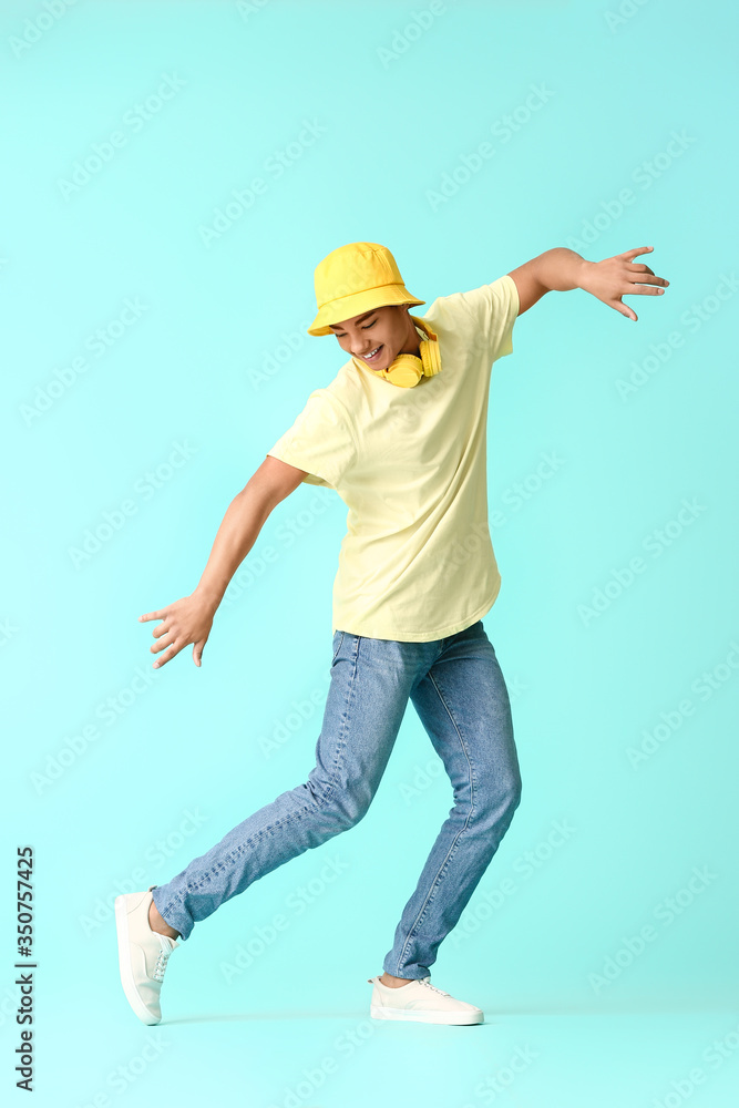 African-American teenager dancing against color background