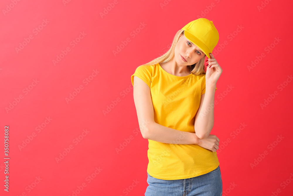 Beautiful young woman in stylish cap on color background