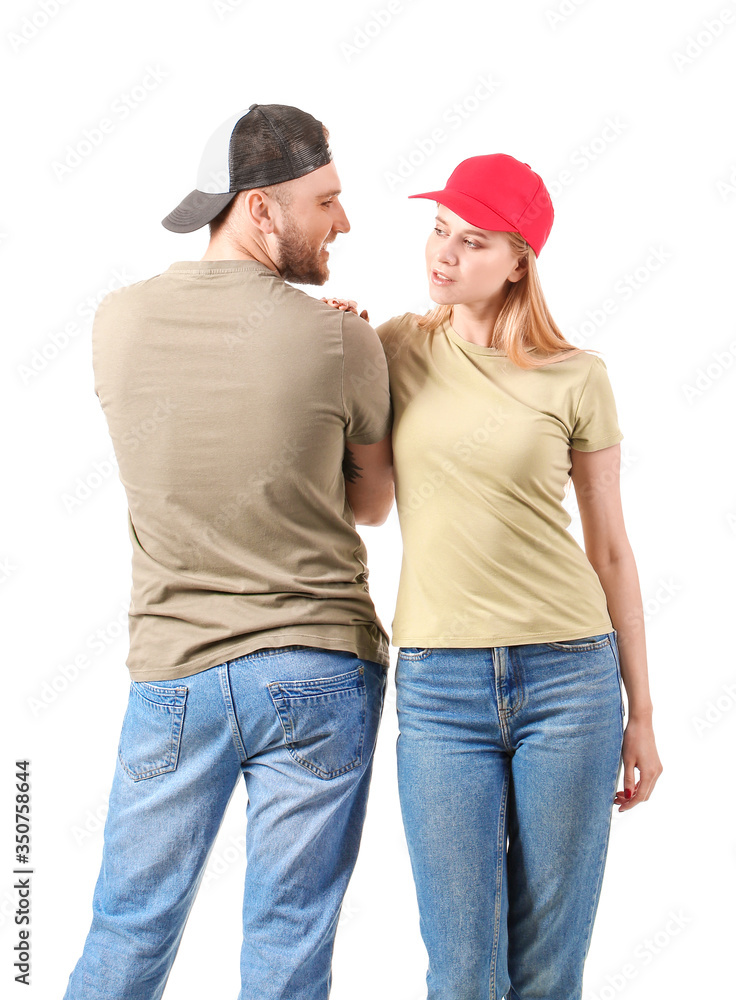 Young couple in stylish caps on white background