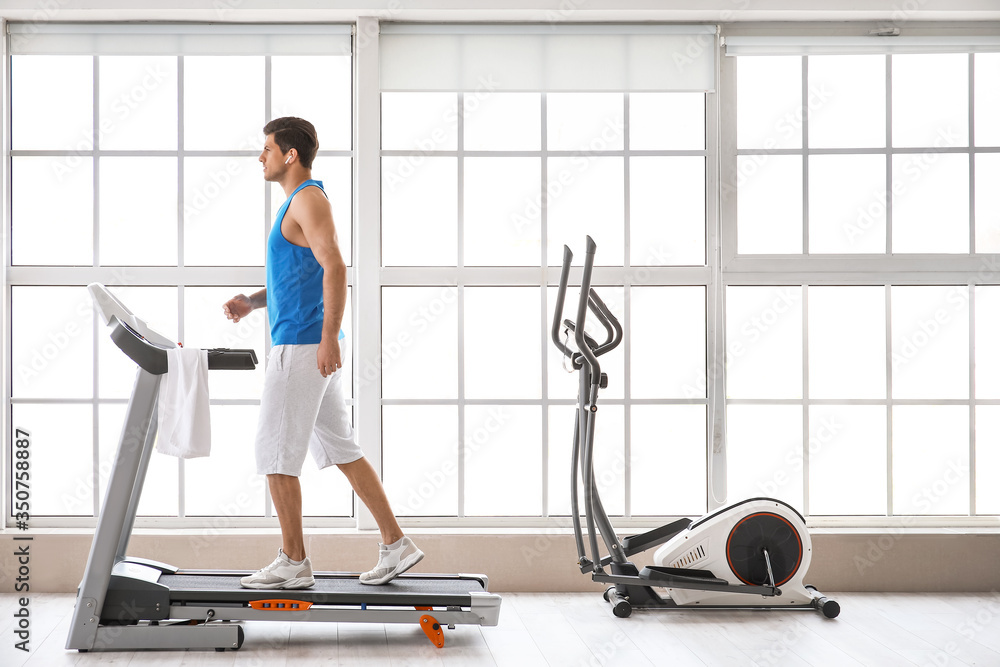 Young man training on treadmill in gym