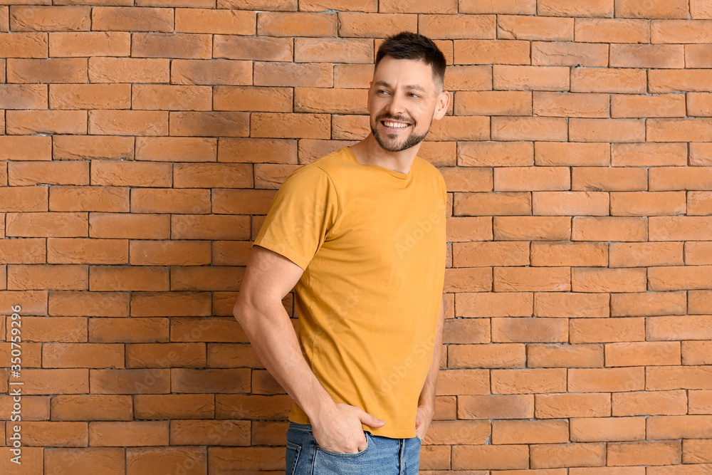 Man in stylish t-shirt near brick wall