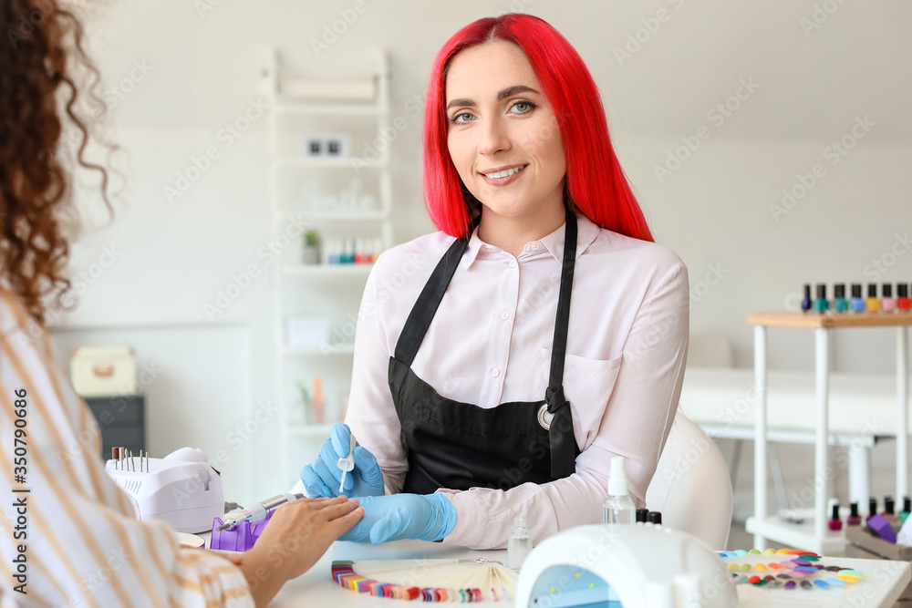 Manicure master working with female client in beauty salon