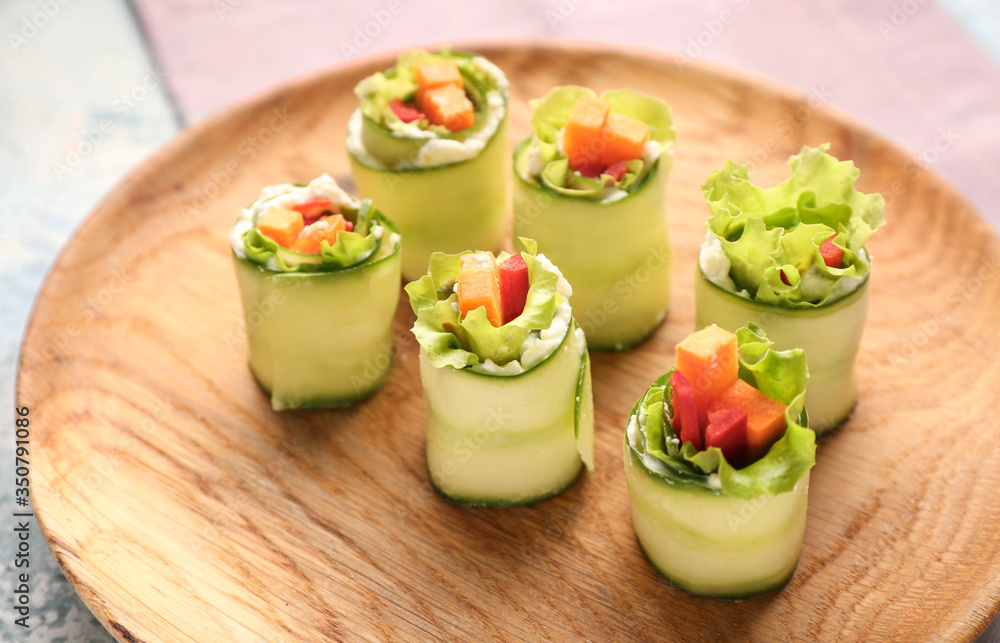 Plate with tasty cucumber rolls on table