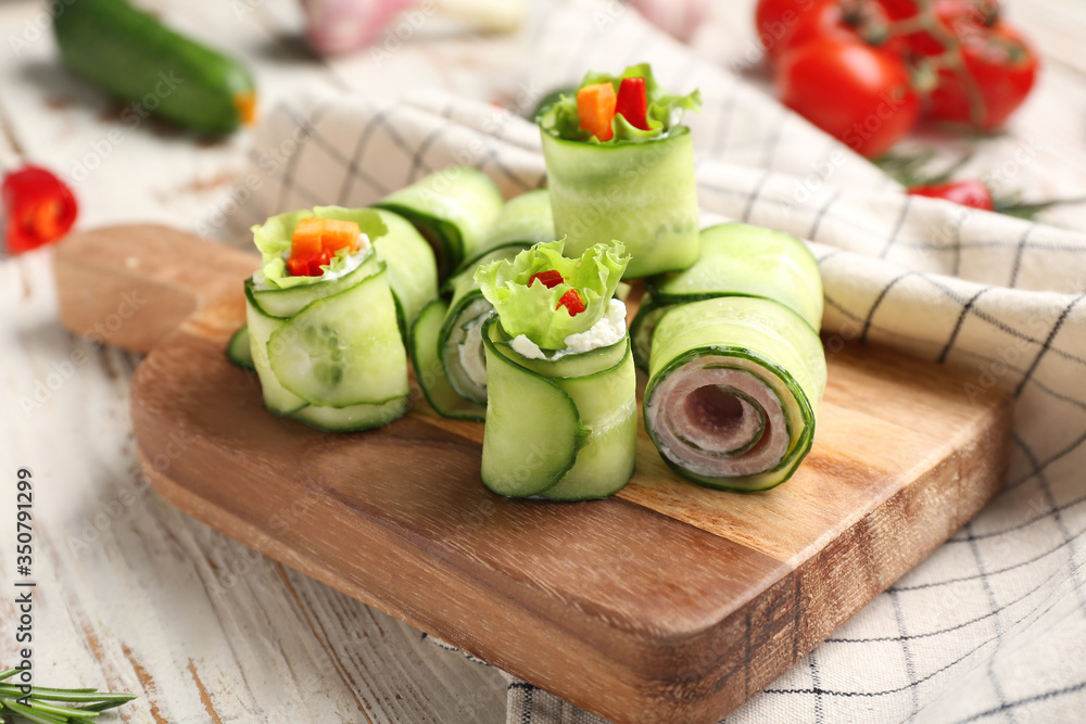 Board with tasty cucumber rolls on table