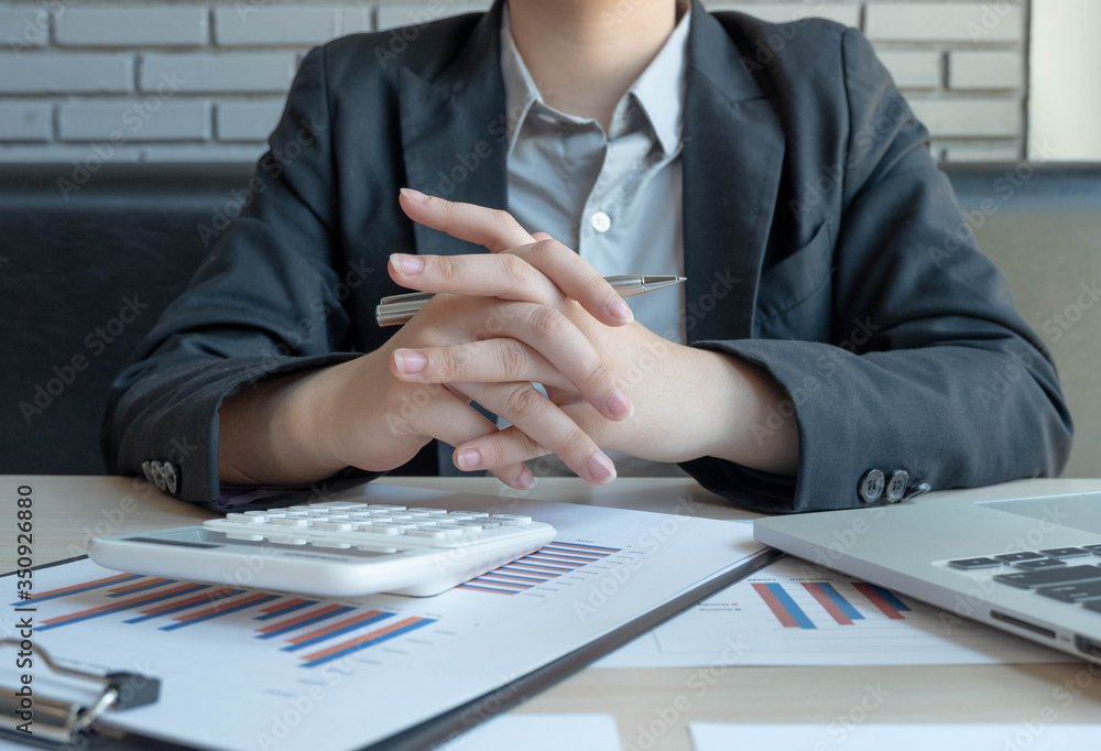 Businesswomen wear black suits, putting both hands together to relieve stress from using a calculato