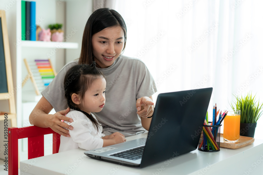 亚洲幼儿园女孩与母亲在笔记本电脑上与老师进行视频会议电子学习