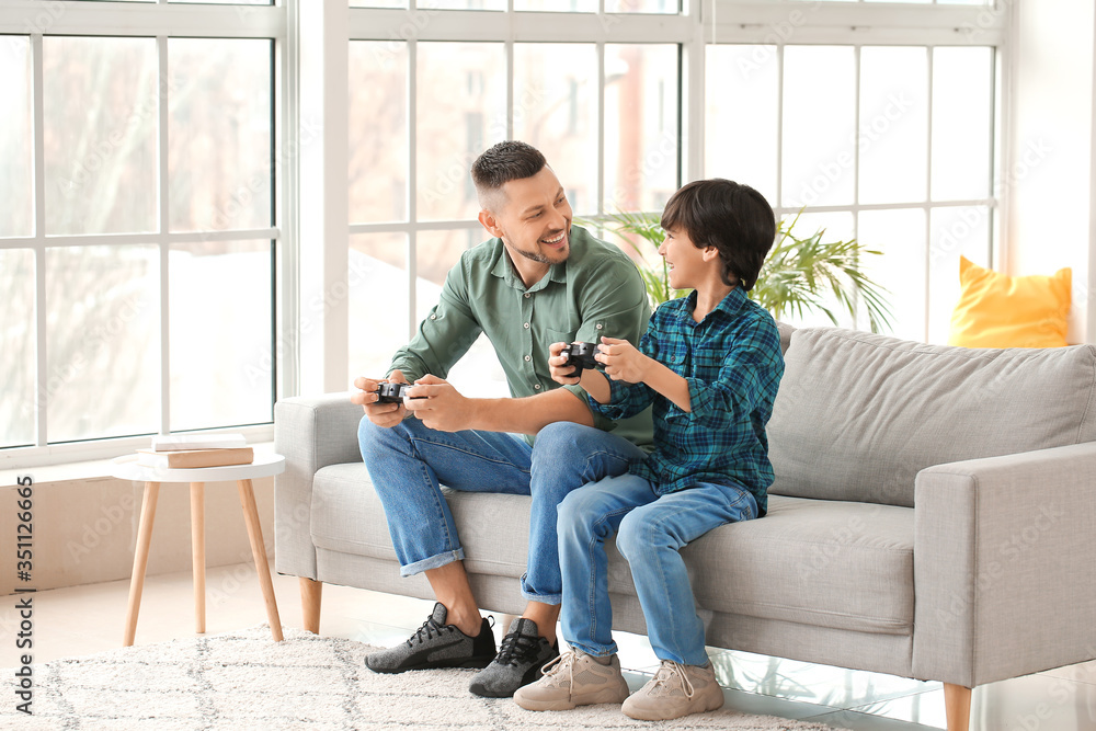 Father and little son playing video games at home