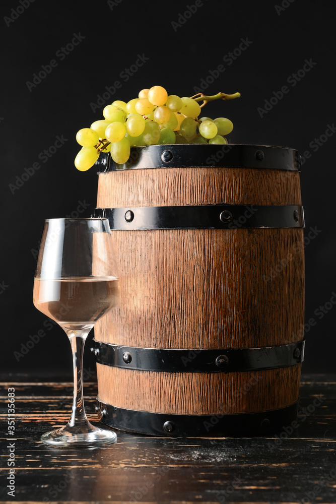 Wooden barrel and glass of wine on dark background