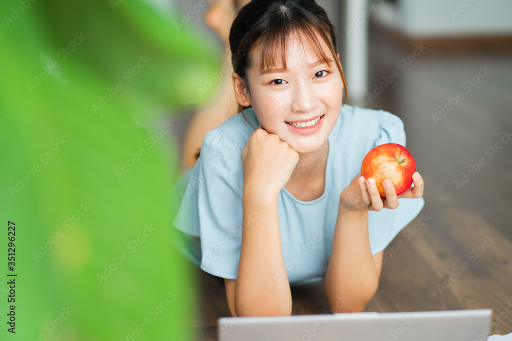 年轻的亚洲女人早上拿着苹果用笔记本电脑