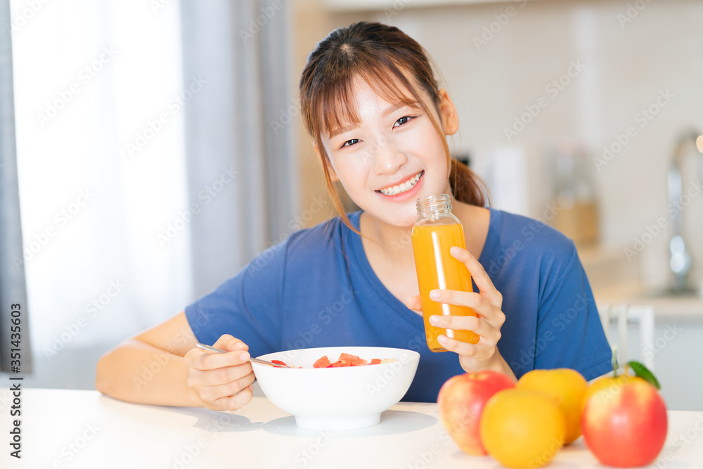 一位年轻的亚洲妇女在厨房里吃水果早餐