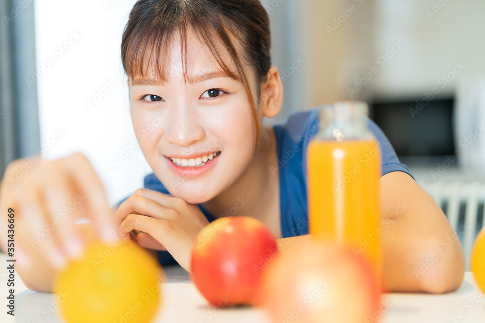 一位年轻的亚洲妇女在厨房里吃水果早餐