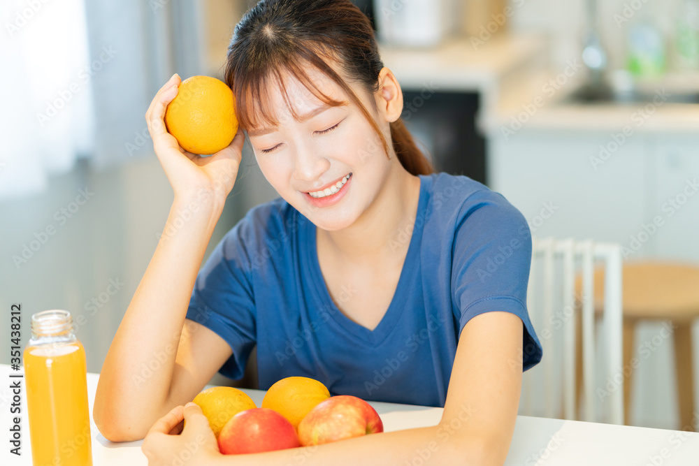 一位年轻的亚洲妇女在厨房里吃水果早餐