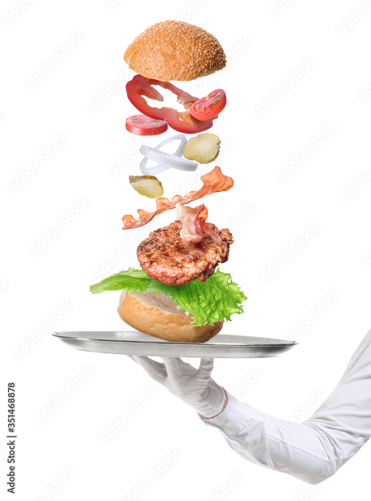 Waiter holding tray with flying ingredients of burger on white background