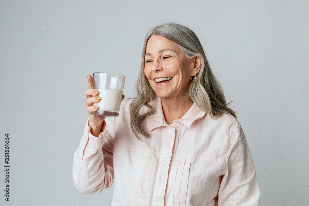 快乐的老年妇女喝着一杯牛奶