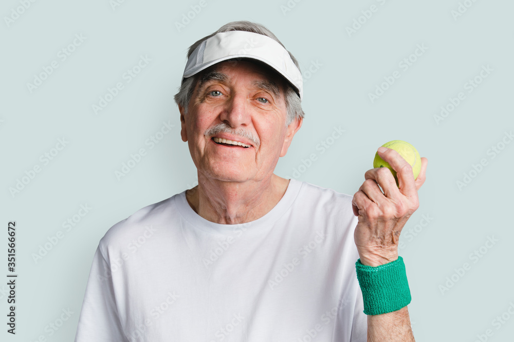 Cheerful senior man with a tennis ball