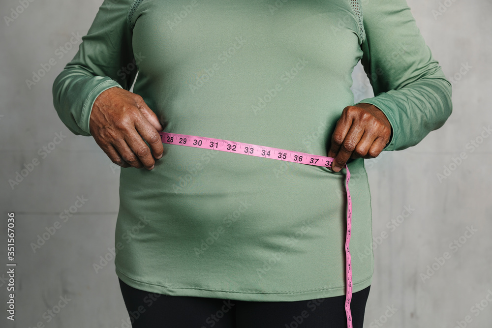 Black woman measuring her tummy