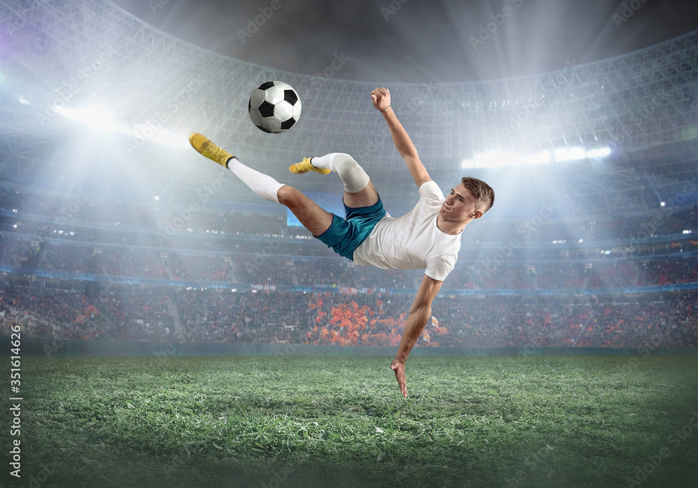 Soccer player on a football field in dynamic action at summer day under sky with clouds. Sporty man 