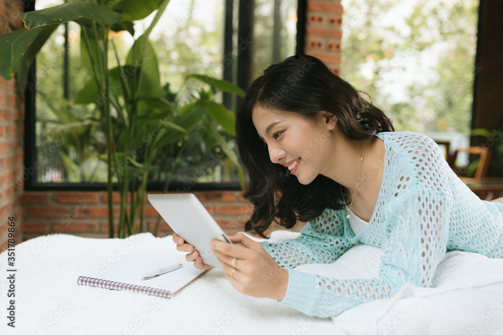 happy young woman with pen and notebook writing in bed at home bedroom