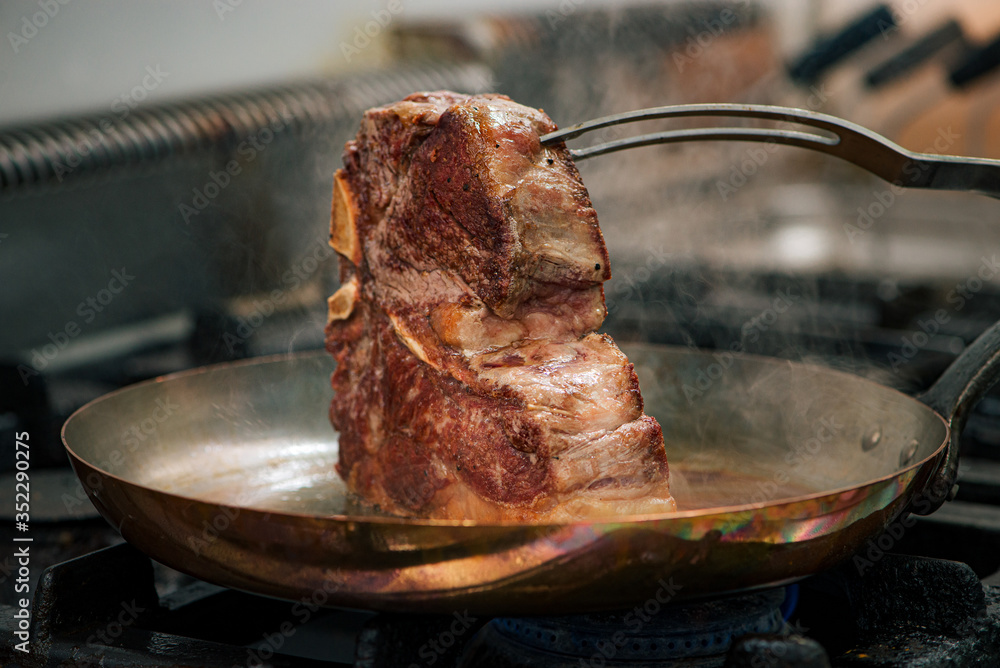 Cooking delicious t-bone steak on a stove.