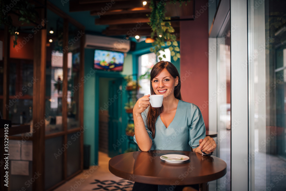 Portrait of a small business owner drinking coffee at her shop.