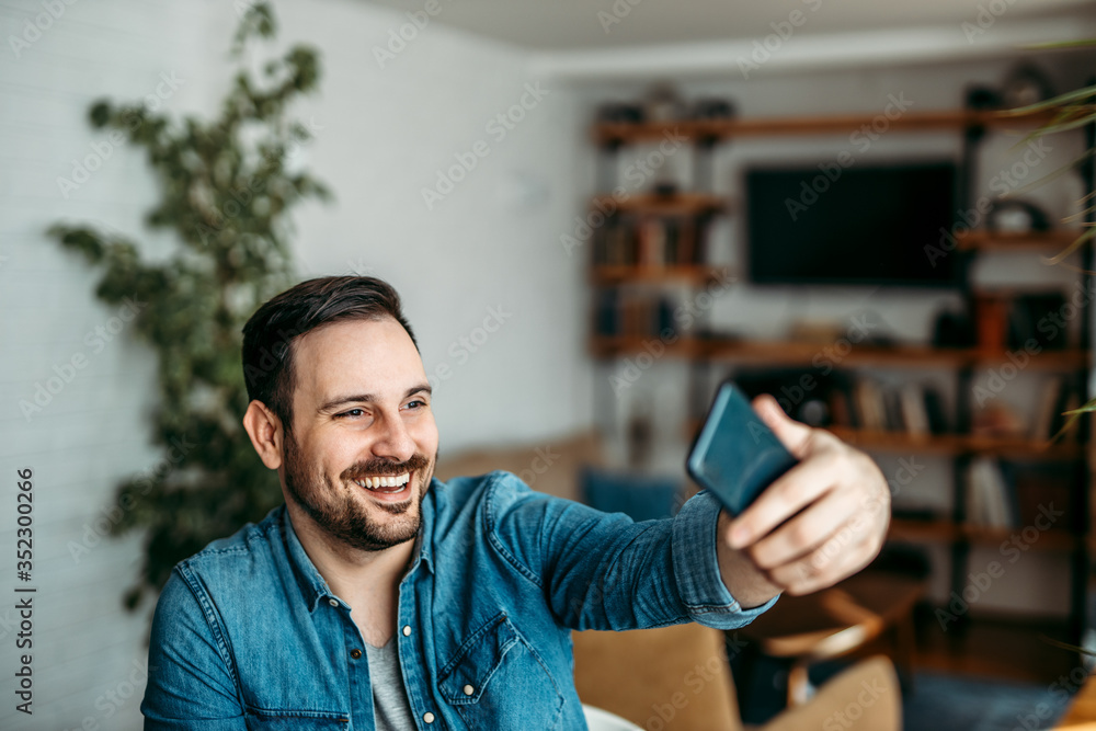 英俊的男人在智能手机上自拍。