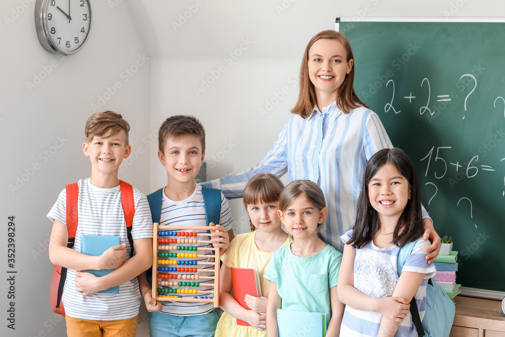 Children with math teacher during lesson in classroom