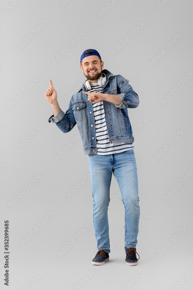 Handsome young man dancing against light background