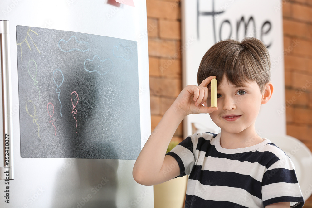 Little boy drawing on chalkboard in kitchen