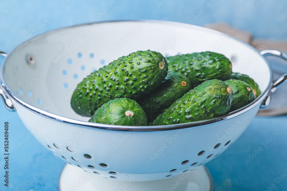 Colander with fresh green黄瓜on color background