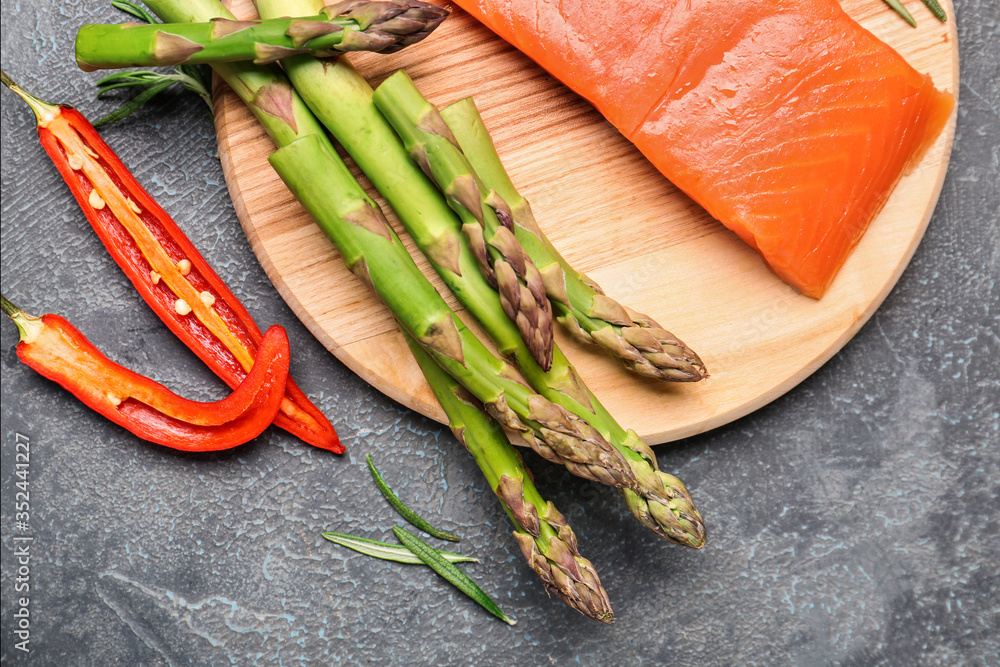 Asparagus with salmon and chili pepper on dark background