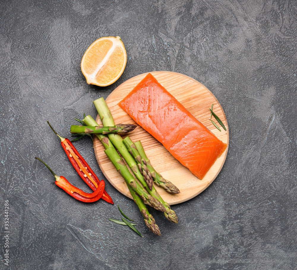 Asparagus with salmon, lemon and chili pepper on dark background