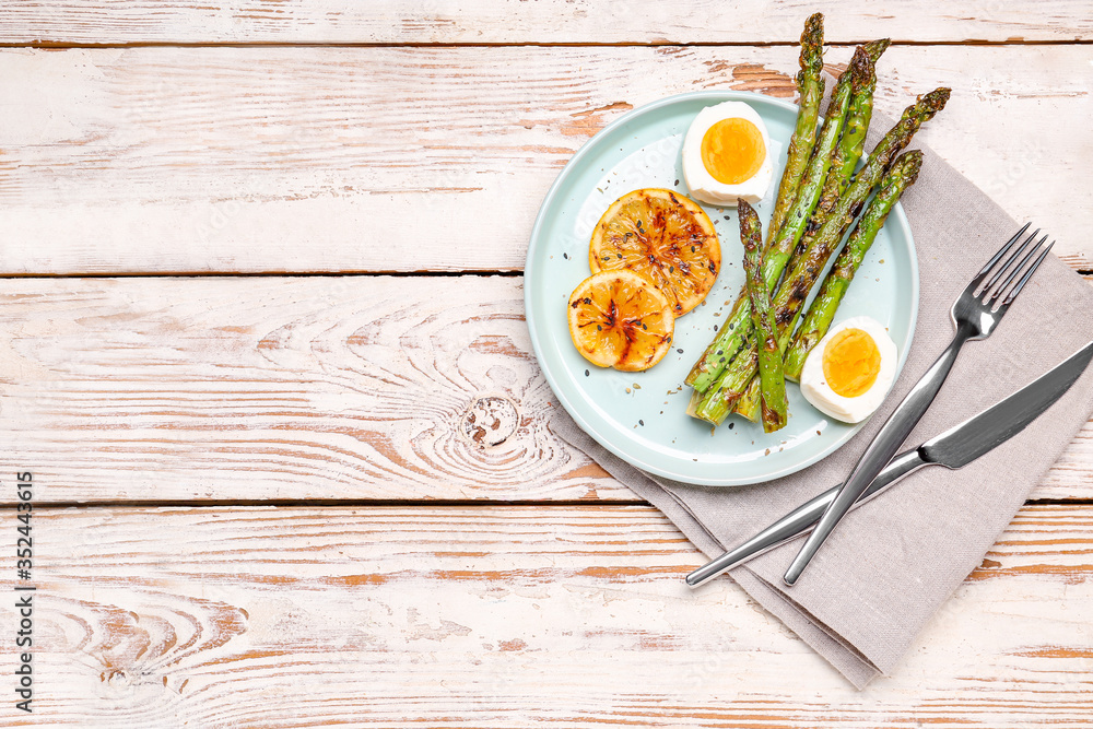 Cooked asparagus with egg and lemon on table