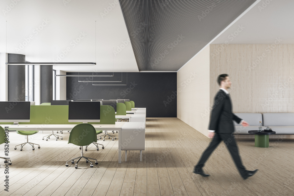 Businessman in suit walking in minimalistic office interior with computers. Workplace and lifestyle 