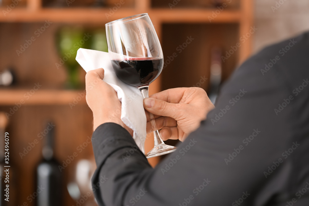 Man with glass of tasty wine and napkin in cellar