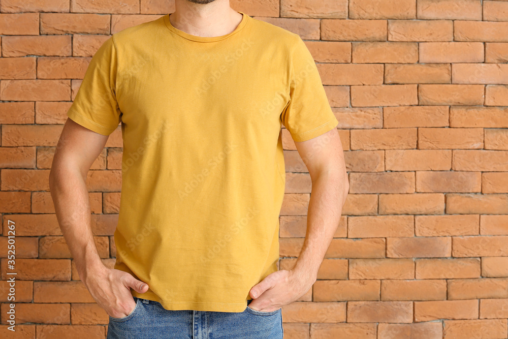 Man in stylish t-shirt near brick wall