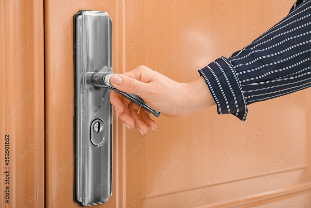 Woman opening door at home, closeup