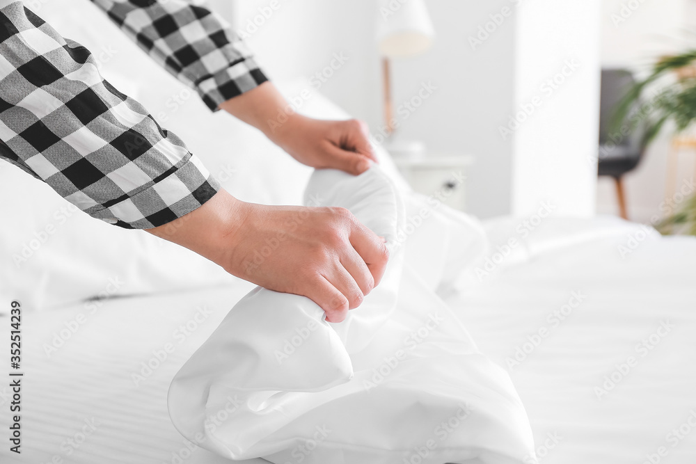 Woman making bed at home