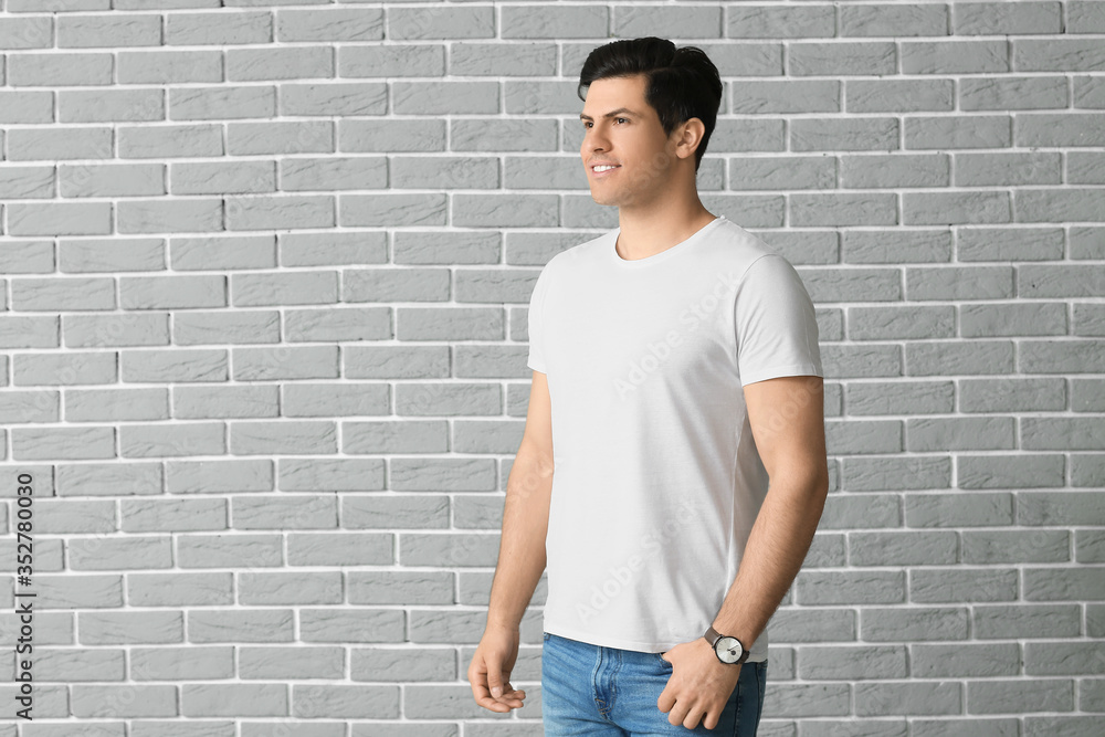 Man in stylish t-shirt on brick background