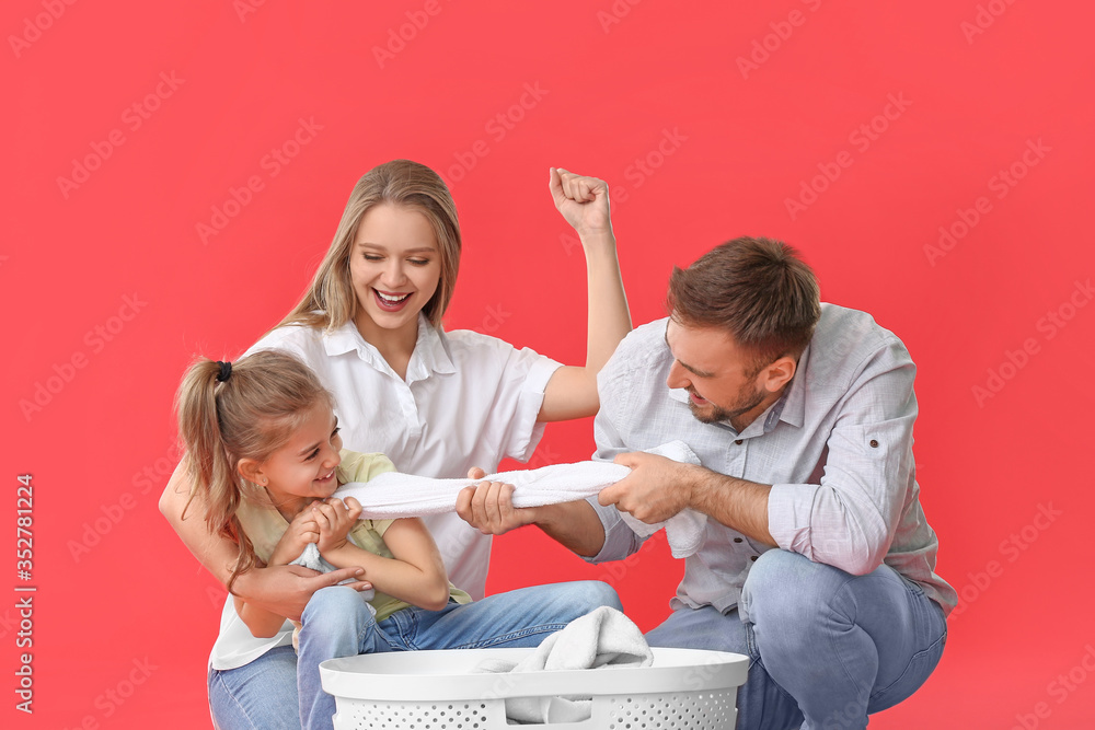 Happy family with laundry on color background