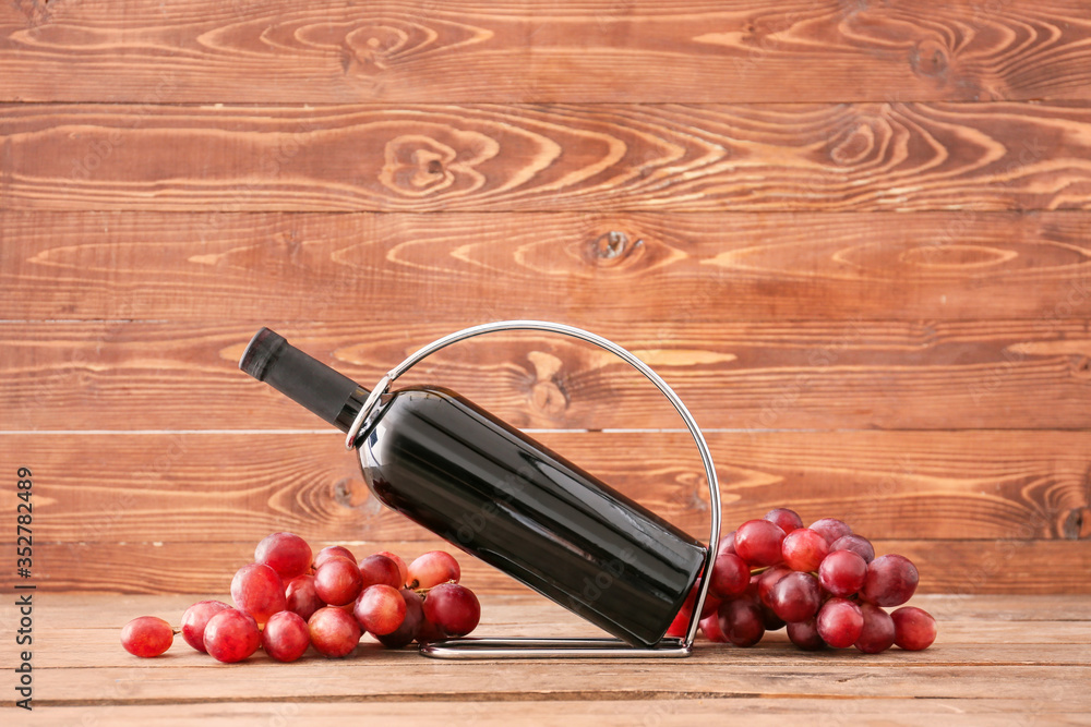 Holder with bottle of wine on wooden background