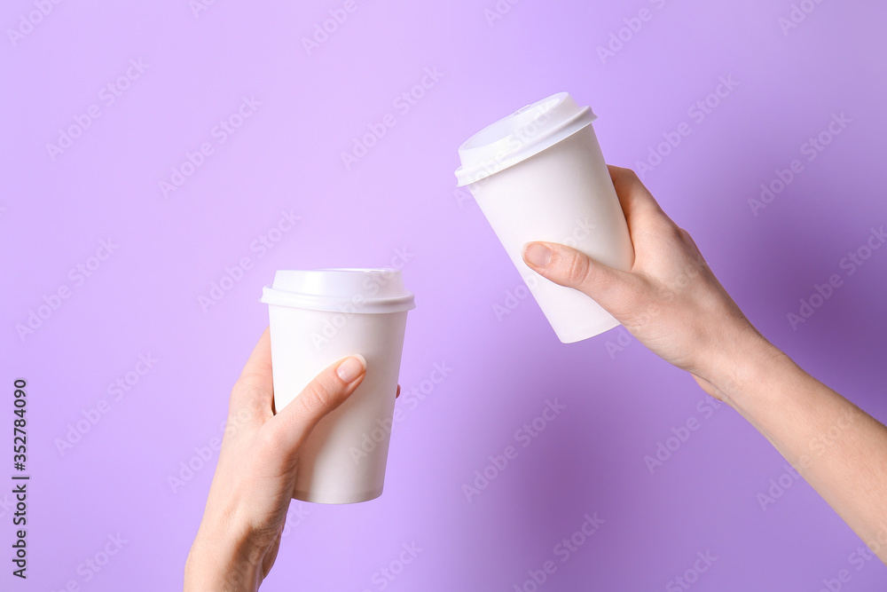 Hands with takeaway cups for drink on color background