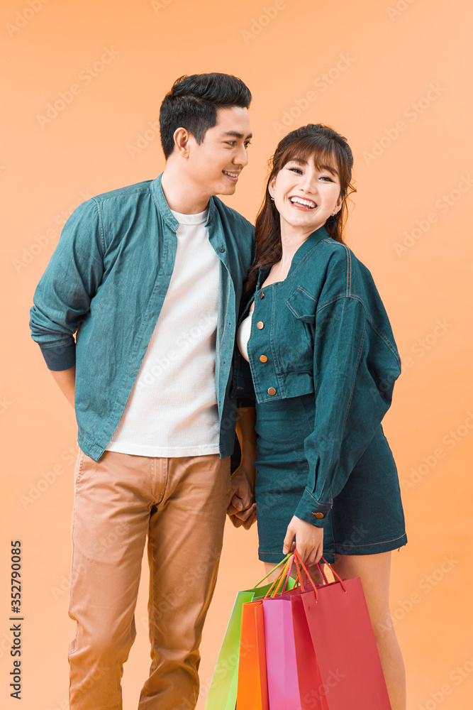 Happy couple with shopping bags, standing close to each other with smile.