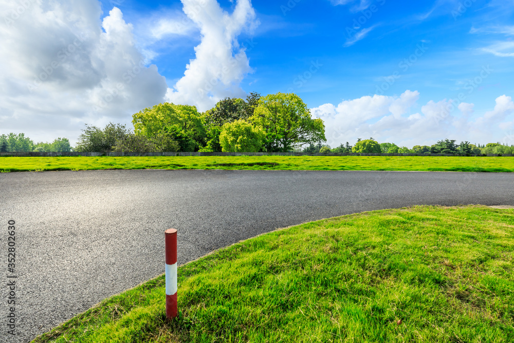 Asphalt road and green forest under blue sky.